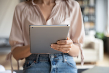 Close up woman using computer tablet at home, standing in modern living room, young female holding...