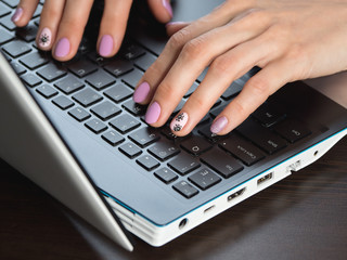 Close-up of typing woman hands with a creative manicure on the theme of coronavirus