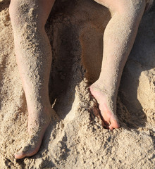 Feet of a man lying on a sunbed near the sea.