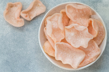 Delicious crispy chips made of starch, flour and shrimp. Bowl of Krupuk (prawn crackers). Traditional Asian snack. A dish of Indonesian, Malaysian, Chinese, Korean, Japanese cuisine. Selective focus