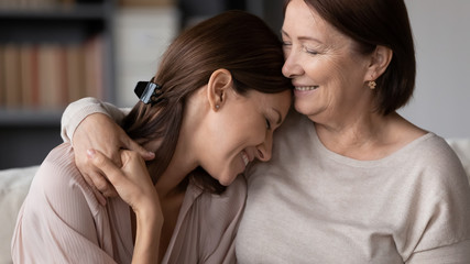 Smiling mature mother hugging adult daughter close up, expressing love and care, family enjoying tender moment, happy young woman and middle aged mum cuddling, two generations good relations