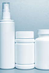 photo of three plastic cans for package pills and vitamins.   photo without bottle labels. blue tinted