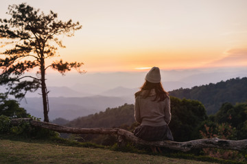 Lonely young woman traveler looking at sunset and beautiful views over the mountain