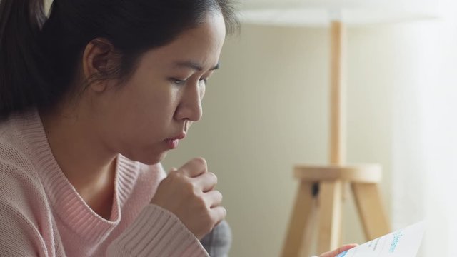 Close up thoughtful asian woman look at bill payment, sad worried stress face at home feeling anxiety depression upset frustrated thinking about personal financial crisis money problem concept.