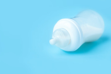 plastic Baby bottle with milk on a pure blue background with copy space.