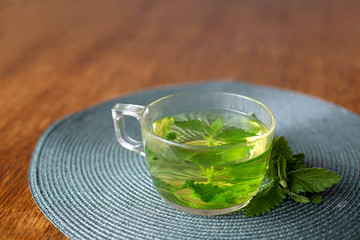 Glass Cup of mint tea. A fragrant tea with fresh leaves of lemon balm. Soothing tea. Aromatherapy. Relax. Morning tea on a wooden table.