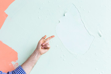 Decorator pointing at cracked wall. Renovation, redecoration and repair concept. Copy space.