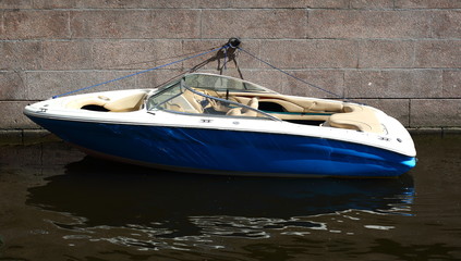 A small motor boat is moored to the granite wall
