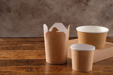 Street fast food paper cups, plates and containers. Eco-friendly food packaging on wooden background. Carering of nature and recycling concept.