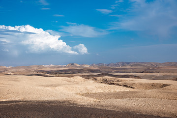Beautiful dry landscape with colorful sand and cloudy blue sky. Dramatic view of the wilderness. The arid landscape of the prairie. Israel Negev Desert Sede Boker. Great view of the Nakhal Tsin rift. 