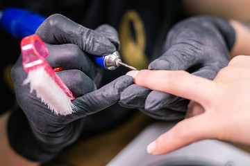 Process manicure close-up. Preparation for hardware manicure. Beautician in rubber gloves cuts the cuticle and processes nails.