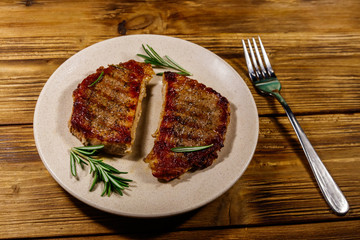 Grilled pork steaks with rosemary on wooden table