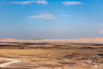 Beautiful dry landscape with colorful sand and cloudy blue sky. Dramatic view of the wilderness. The arid landscape of the prairie. Israel Negev Desert Sede Boker. Great view of the Nakhal Tsin rift. 