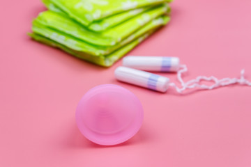 Sanitary pad, tampons and menstrual cup on pink background. Concept of critical days, menstruation, feminine hygiene