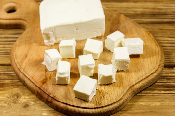 Feta cheese on cutting board on a wooden table