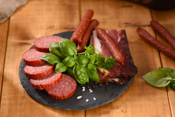 Ham and smoked sausage cutting on a slate plate. A snack in between.