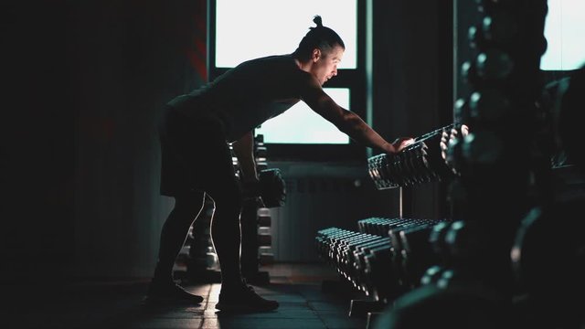 athletic man with perfect torso exercising with dumbbells in gym