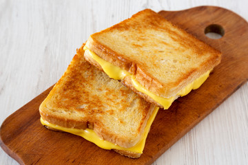 Homemade Grilled Cheese Sandwich on a rustic wooden board on a white wooden background, low angle view. Close-up.