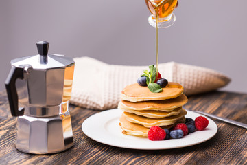 Close-up of pouring maple syrup on stack of pancakes.