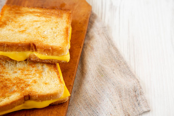 Homemade Grilled Cheese Sandwich on a rustic wooden board on a white wooden background, side view. Copy space.
