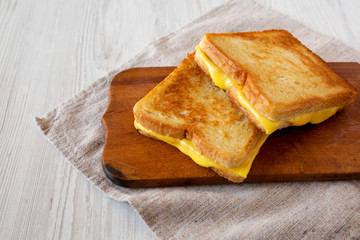 Homemade Grilled Cheese Sandwich on a rustic wooden board on a white wooden surface, low angle view. Copy space.