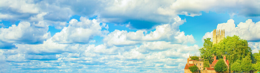 Narrow horizontal background with a panorama with an old castle on a hill and a blue sky with clouds on the theme of tourism in Europe or the Middle Ages. Substrate for website header or blog title. © Николай Батаев
