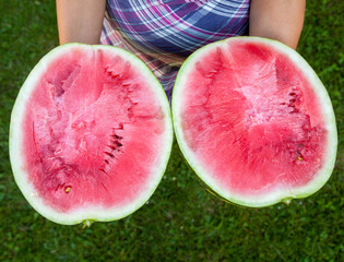 Woman holding a watermelon cut into halves.