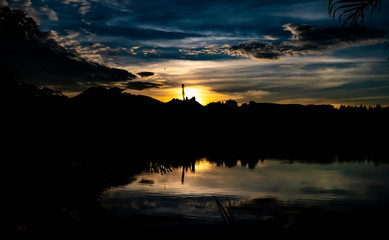 Sunset with silhouette trees and reflection in lake