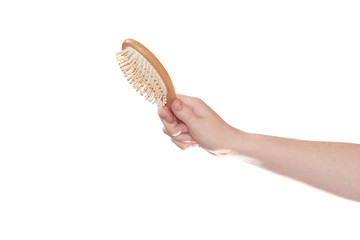 Hand of a red-haired girl with freckles with a massage comb isolated on a white background and with a clipping path