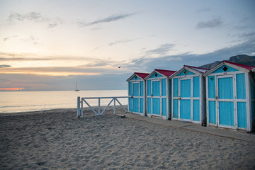 Little blue houses on the beach. A place to store beach utensils. Rasset (sunset) on the Mediterranean coast. The concept of a relaxing beach holiday. Old cracked paint