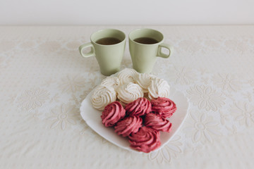 green tea cups for two white marshmallows in a white plate