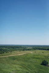 Obraz premium field road on a green hill and blue sky