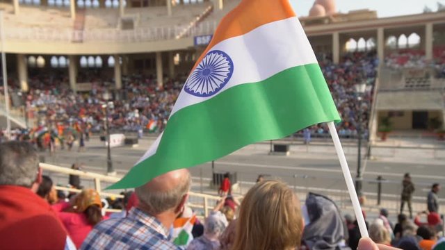 Close up of India National Flag in Arena With Crowds of Indian People With Flag in Background