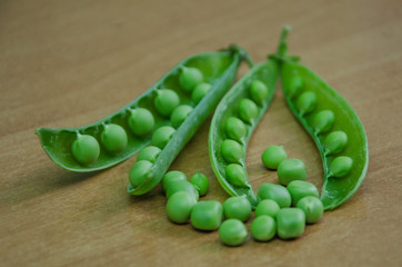 Pods of green peas with peas on a wooden background. Natural foods.