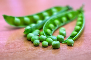 Pods of green peas with peas on a wooden background. Natural foods.