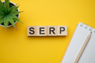 Modern marketing buzzword SERP - Search engine results page. Top view on wooden table with blocks. Top view.