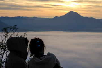 Silhouette of  the lovers watching on sunrise and mist at Phu Tok,Loei province,Thailand. Concept of Love and Commitment