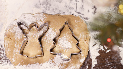 cookie cutters shape christmas tree and angel lie on raw dough with spices for gingerbread on table covered with flour and candy, christmas