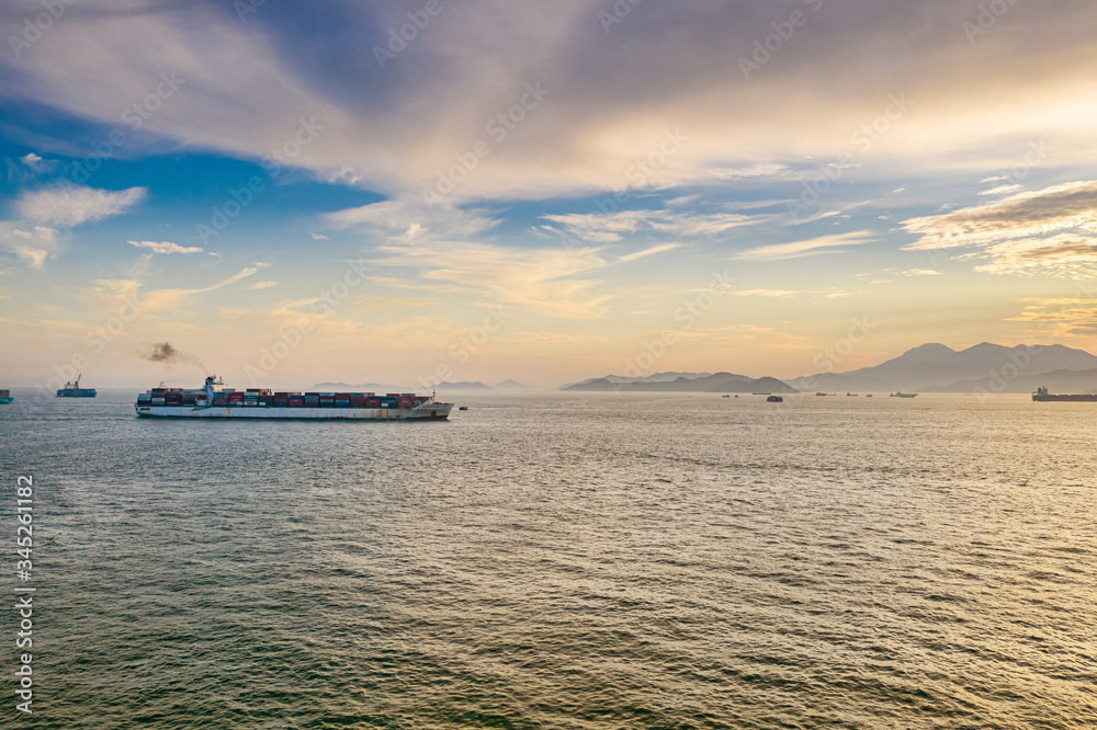 Wall mural Container ships pass in and out Victoria Harbour at dusk