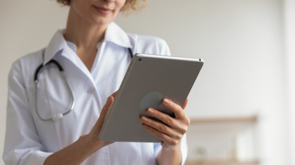 Female professional medic doctor holding modern pad using digital tablet remote telemedicine app in...