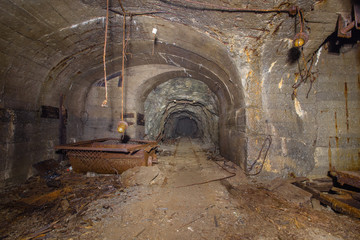 Underground abandoned iron ore mine tunnel with concrete timbering and rails