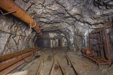 Underground abandoned iron ore mine tunnel with concrete timbering and rails