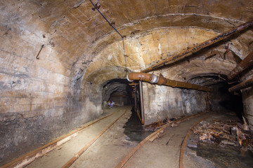 Underground abandoned iron ore mine tunnel with concrete timbering and rails