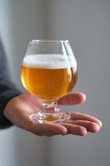 A glass of beer in the hands of a man. Tasting brewed craft beer. Lager beer with beautiful foam. Cold refreshment beverage. Alcohol drink from pub. Relaxation and enjoyment on beer degustation