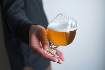 A glass of beer in the hands of a man. Tasting brewed craft beer. Lager beer with beautiful foam. Cold refreshment beverage. Alcohol drink from pub. Relaxation and enjoyment on beer degustation