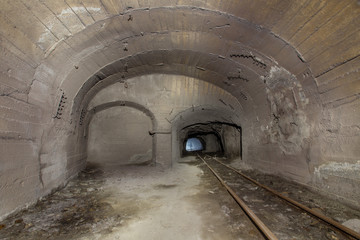 Underground abandoned iron ore mine tunnel with concrete timbering and rails