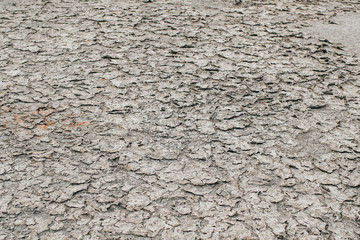 Dry land soil or cracked ground texture and parched dirt in Thailand.Mosaic pattern of sunny dried earth soil.Desert,Global warming made climate change effect background.Water shortage and drought.