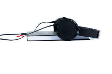 Black headphones and a book isolated on white background. Audiobook concept copy space.