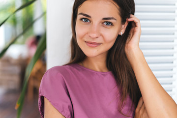 Close-up portrait of beautiful young brunette woman in modern white style cafe.