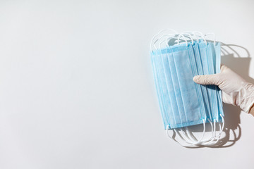 Woman hands in latex gloves holding facial medical masks, white background, close up